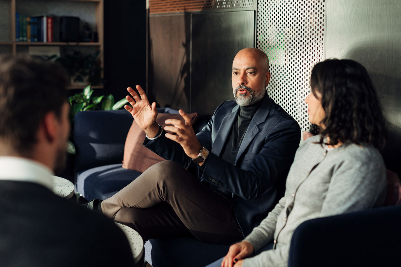 man in office explaining something with is hands, woman and man listening