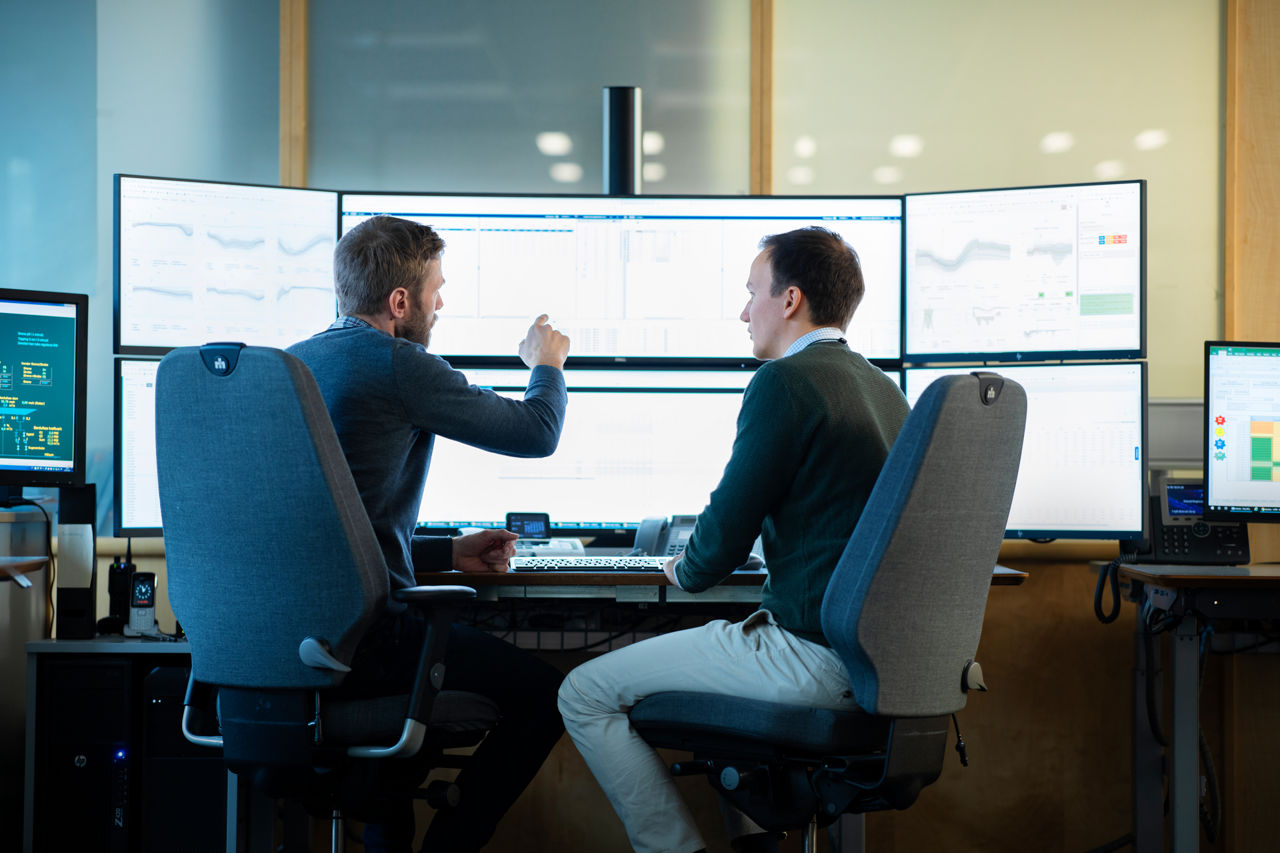 two men in the office looking and pointing at PC screens